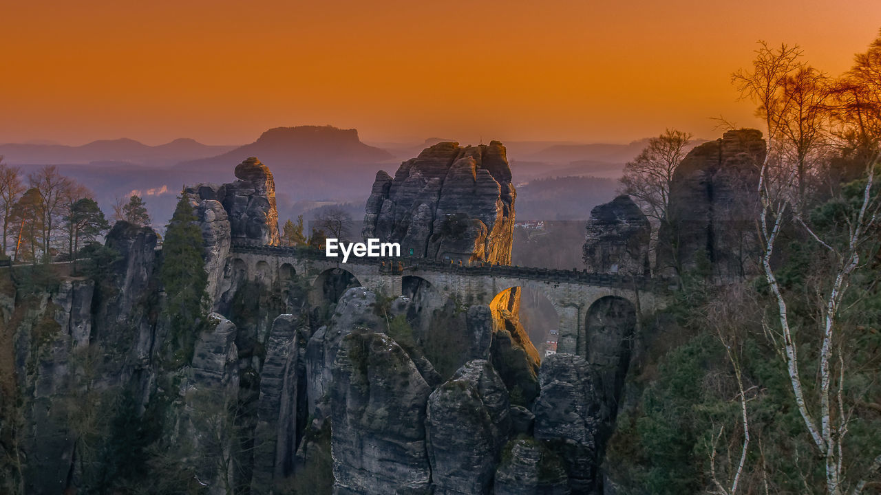 Panoramic shot of bridge over sea against orange sky