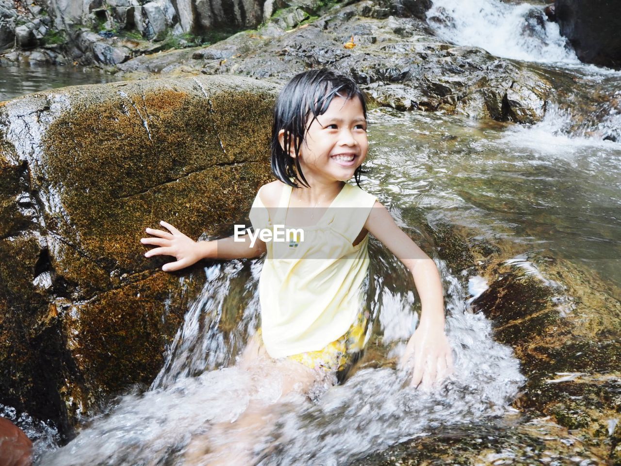 PORTRAIT OF SMILING GIRL ON ROCK