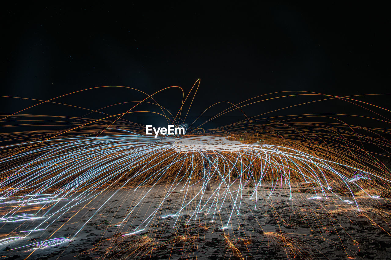 Person spinning wire wool at night