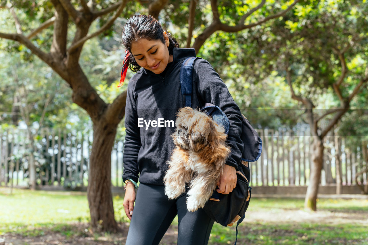 Side view of young woman with dog on field