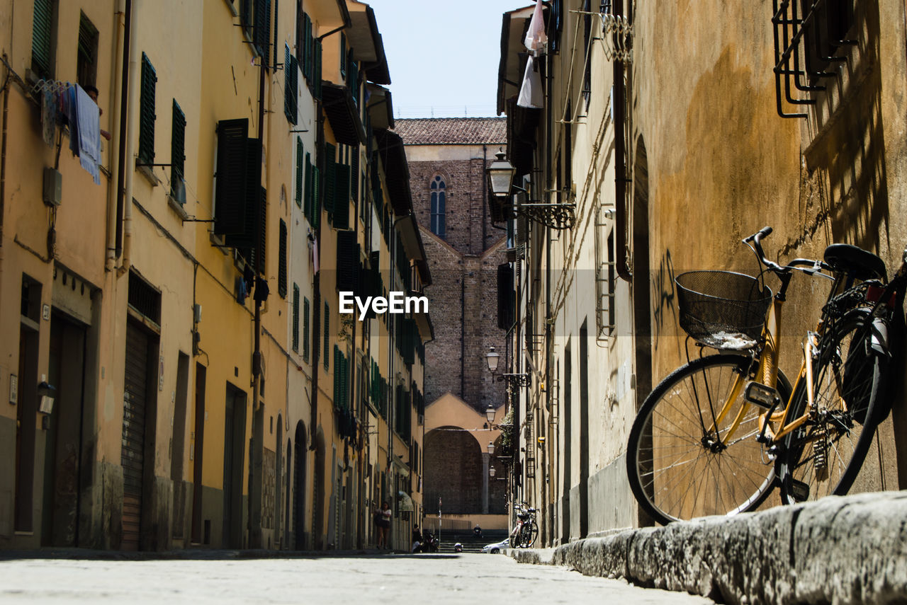 BICYCLE PARKED ON ROAD AMIDST BUILDINGS