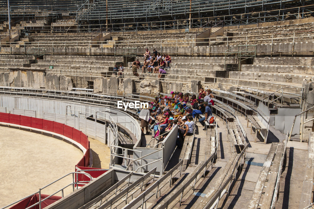 A group of tourists resting on the steps of the ancient amphitheater.
