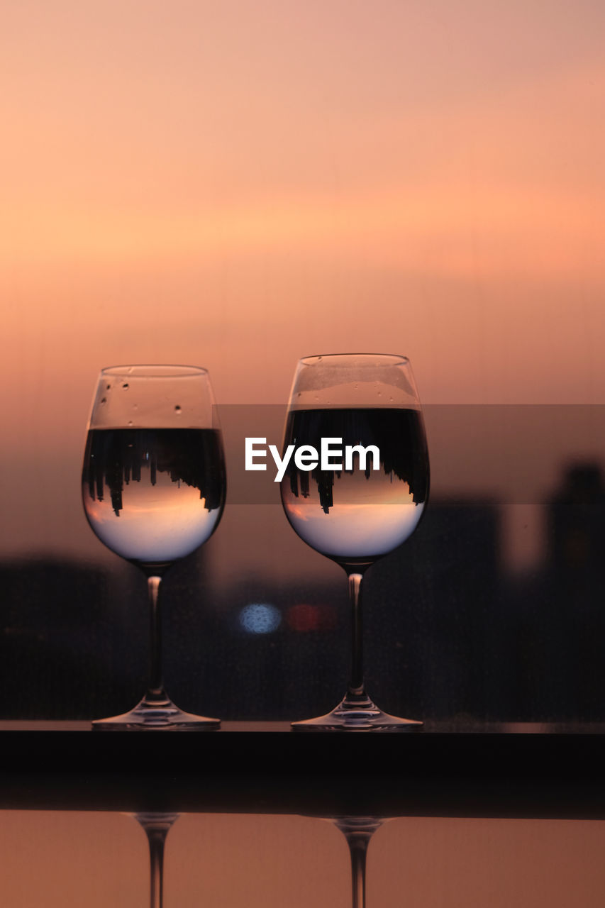 Close-up of wine glass on table against sky during sunset