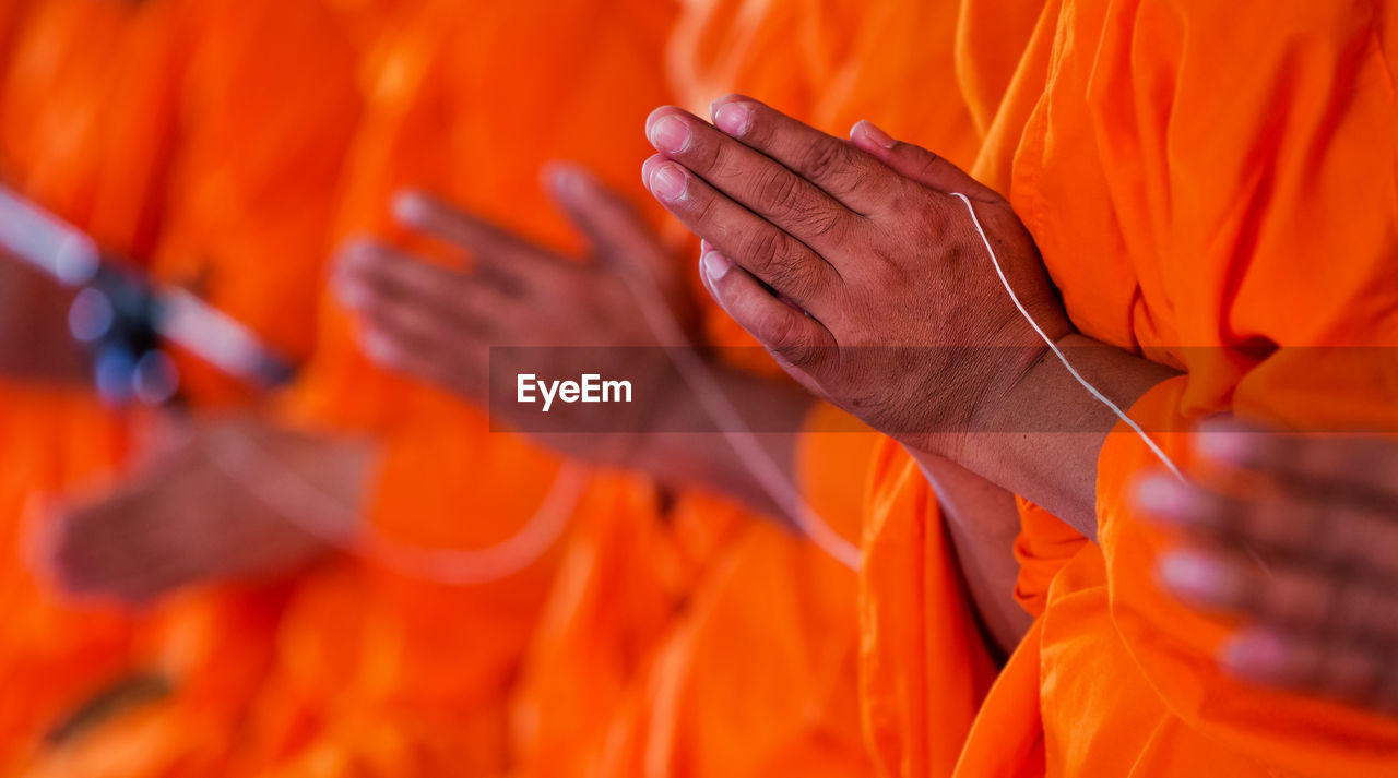 Midsection of monks with hands clasped