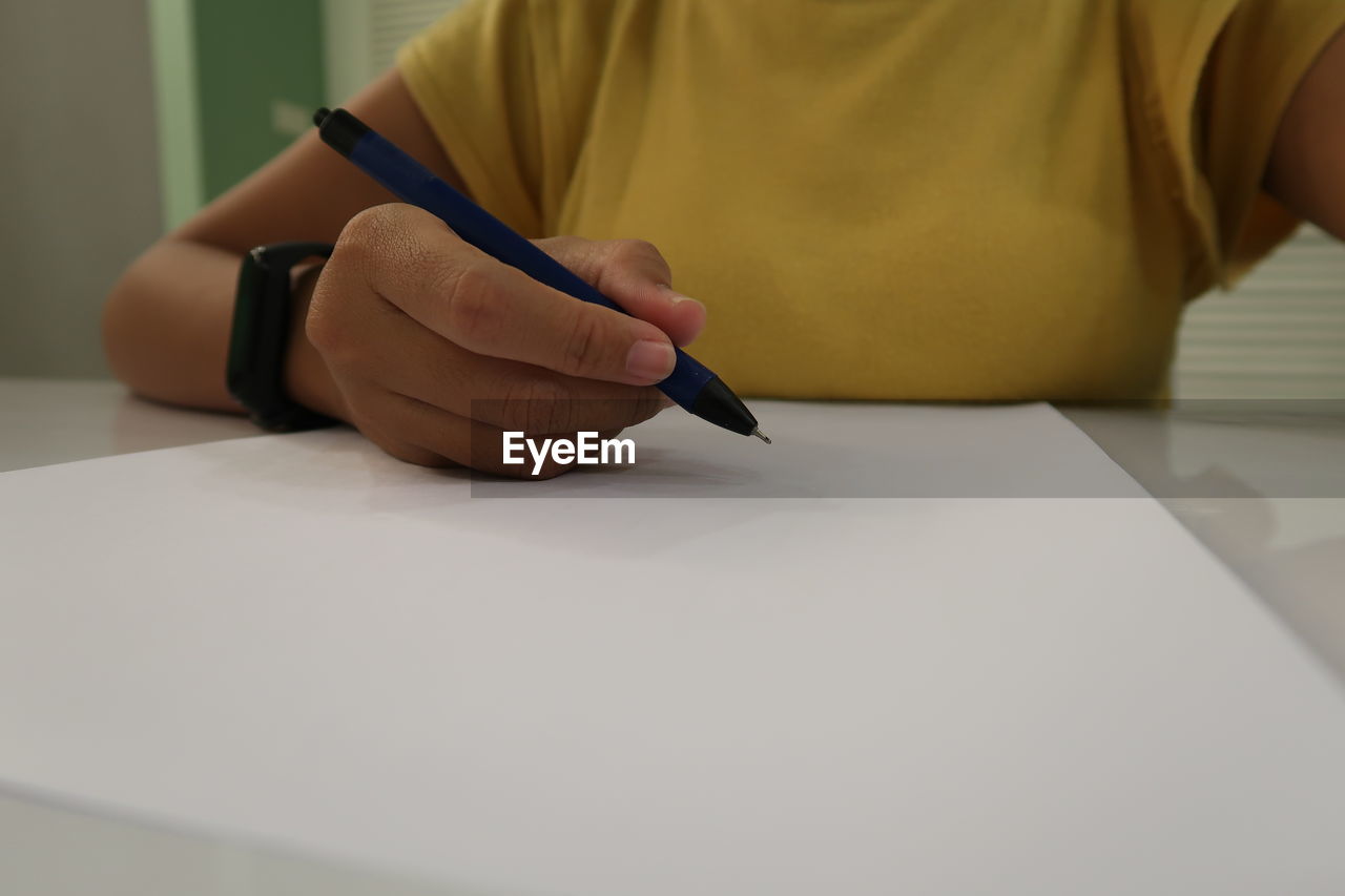 Midsection of woman holding paper while sitting on table