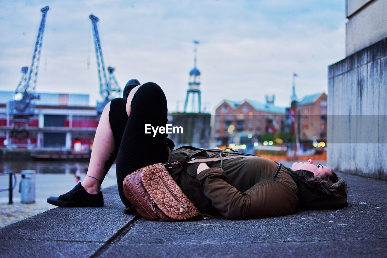 Young woman lying on footpath by river