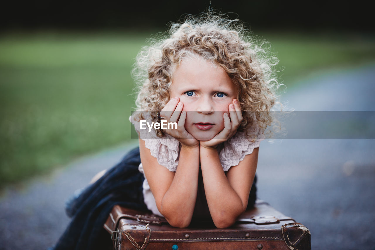 Portrait of beautiful blonde girl with curls with hands on her face