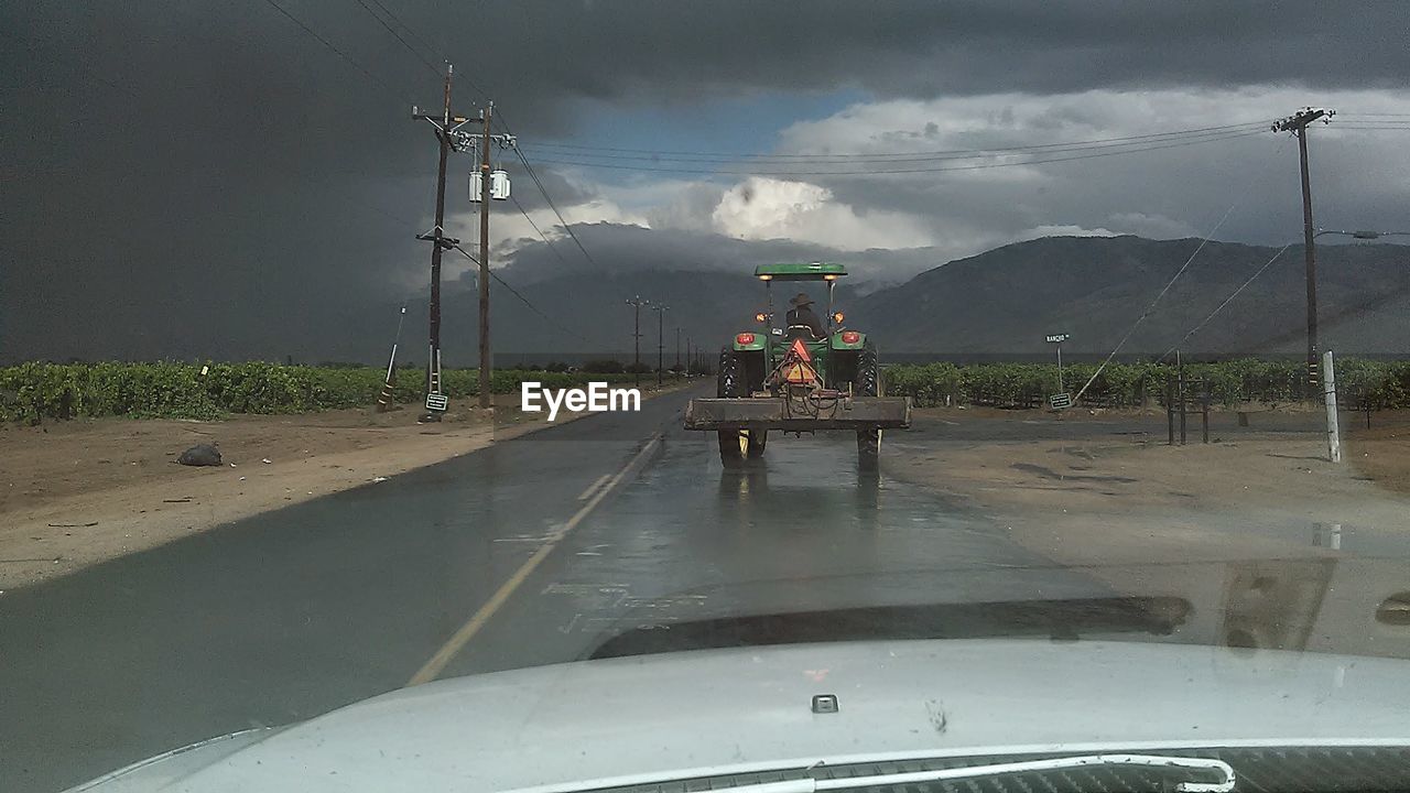 Cars on road against cloudy sky