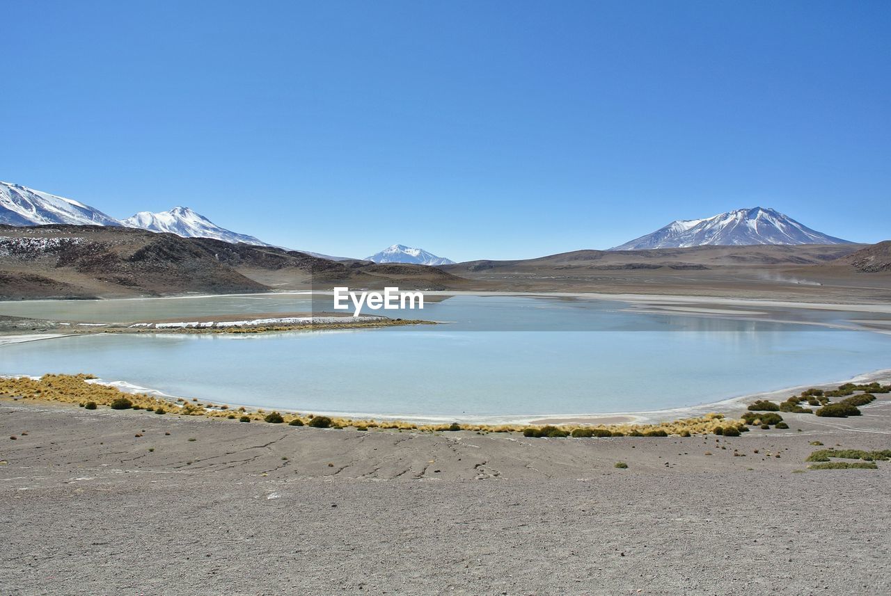 Scenic view of lake against clear blue sky