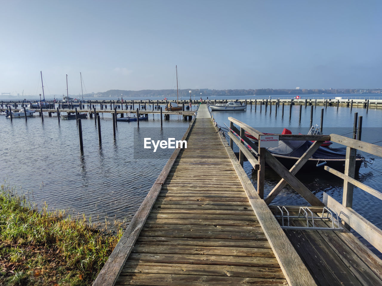 water, pier, dock, sky, sea, walkway, wood, transportation, nature, architecture, shore, nautical vessel, tranquility, beach, boardwalk, jetty, land, coast, tranquil scene, beauty in nature, scenics - nature, built structure, no people, travel destinations, travel, day, environment, harbor, clear sky, bridge, landscape, outdoors, idyllic, mode of transportation, marina, in a row, non-urban scene, tourism, horizon, diminishing perspective, the way forward, holiday, bay, seascape, moored, sunlight, trip, channel, vacation, horizon over water, body of water, coastline, ocean, post, vehicle, sunny, blue, building exterior