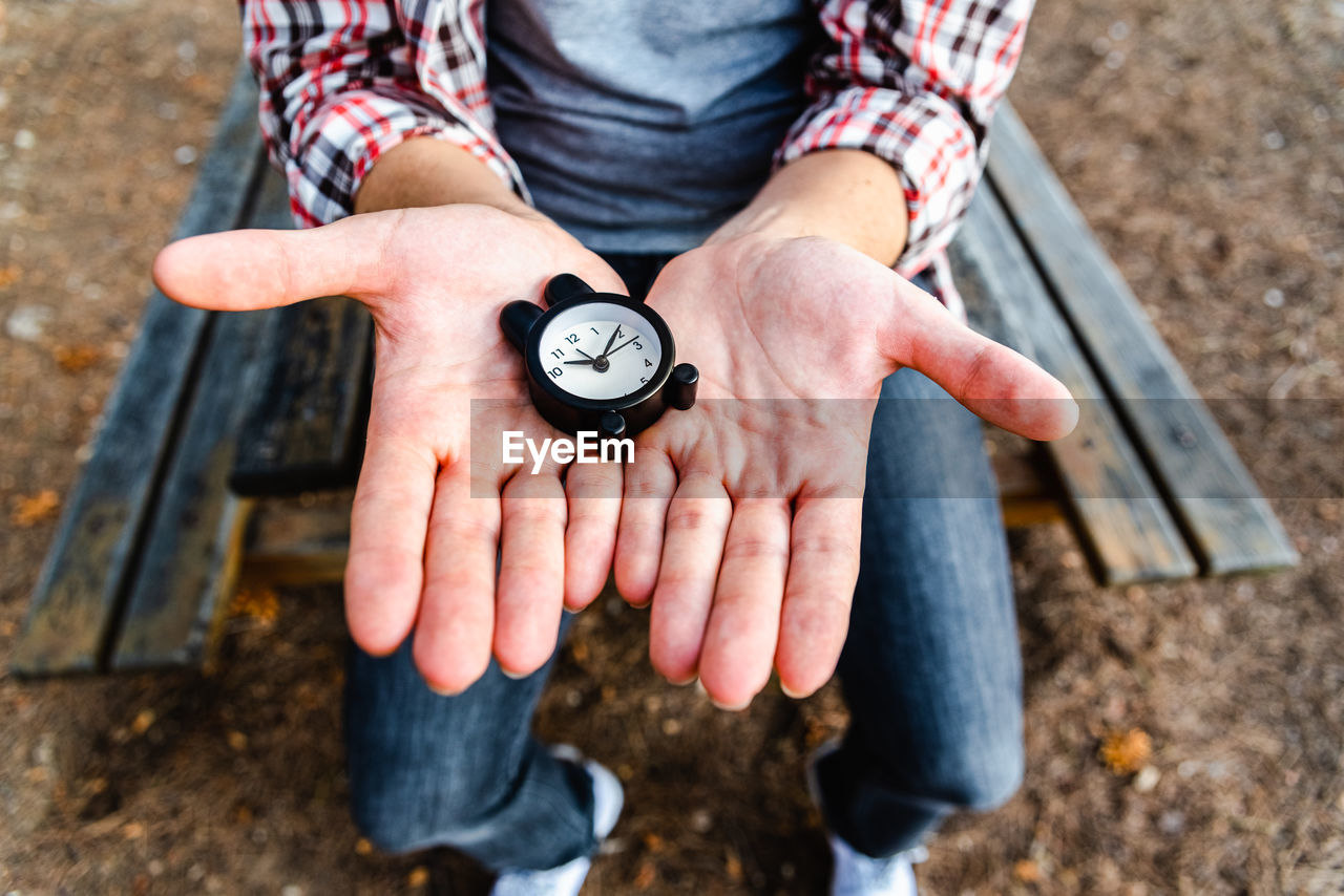 Midsection of person holding clock