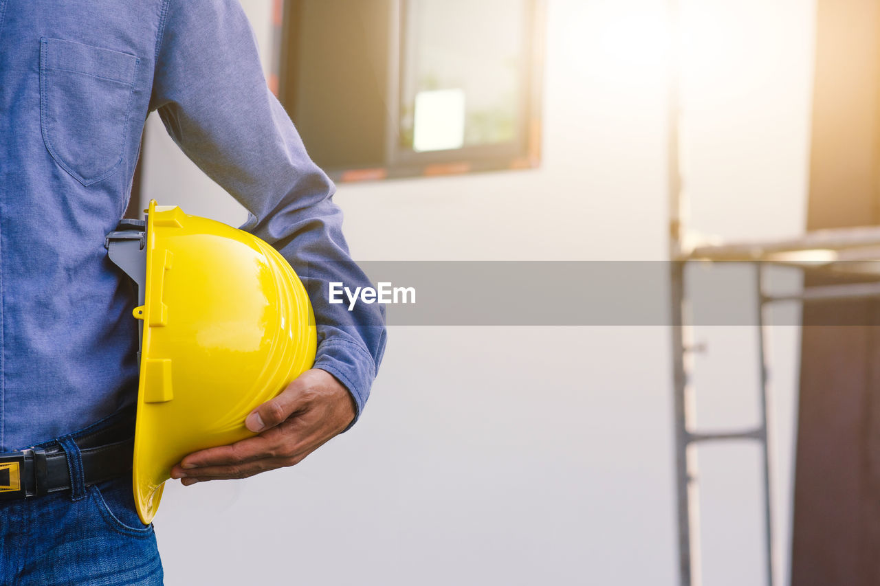 MIDSECTION OF MAN WORKING ON CONSTRUCTION SITE