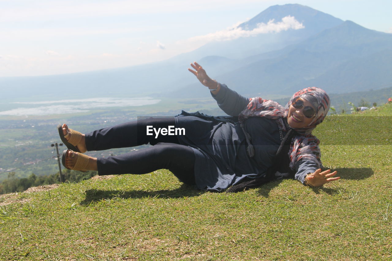 Full length of woman lying on grass against sky