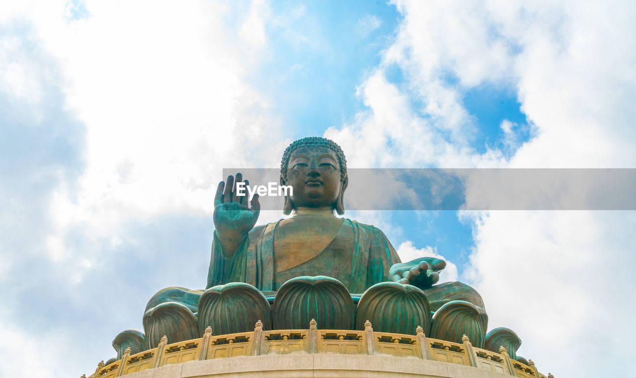 Low angle view of buddha statue against sky