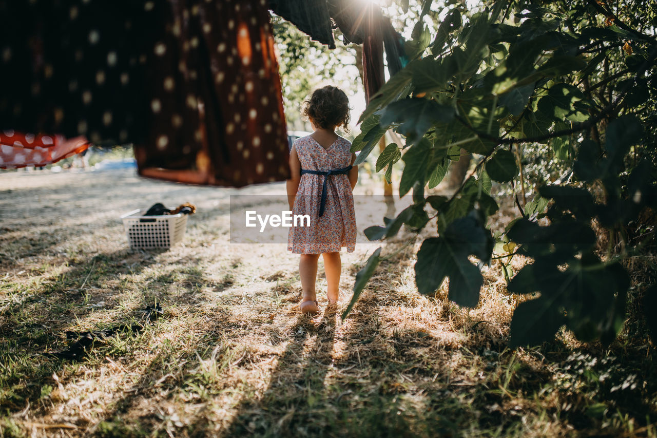 Rear view of girl standing by plants outdoors