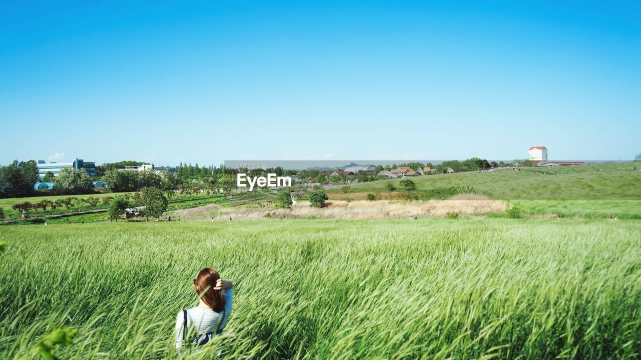 Woman amidst plants on field against sky