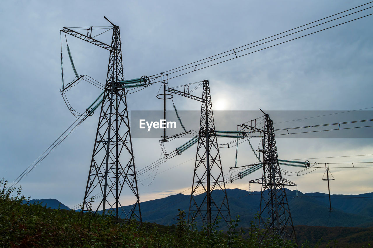 Low angle view of electricity pylon against sky during sunset