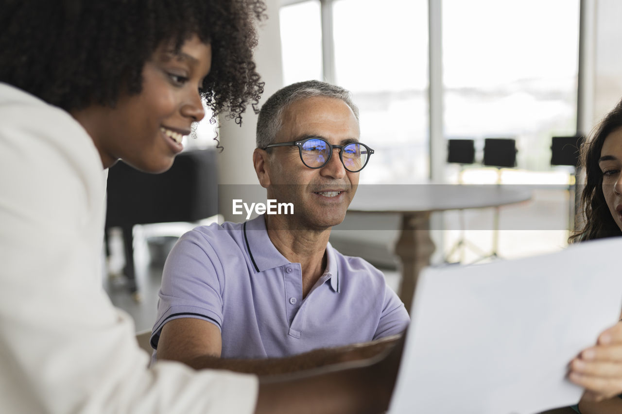 Smiling mature businessman discussing document with businesswomen