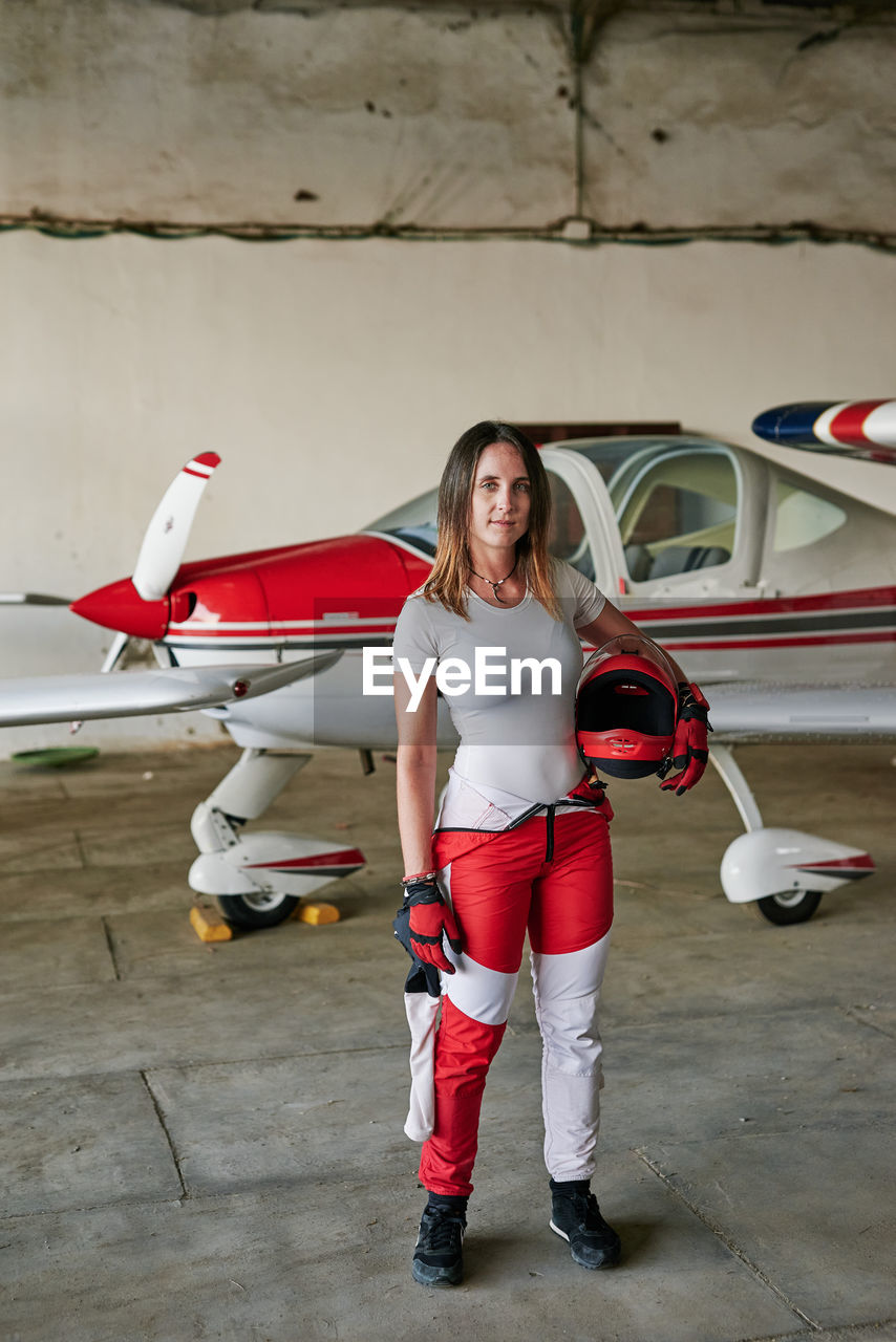 Young female skydiver in a plane hangar with a helmet