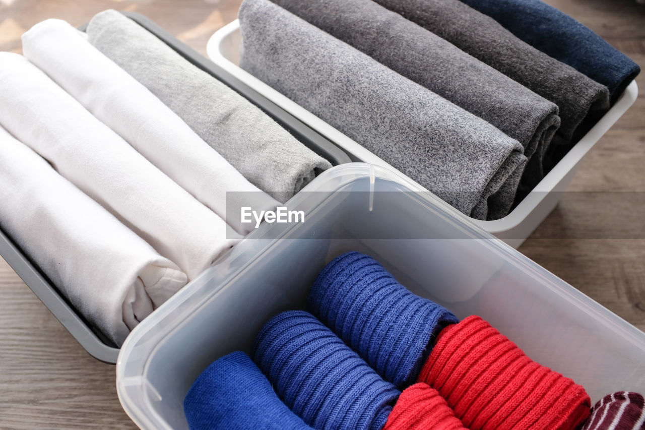 High angle view of folded clothing in containers on hardwood floor