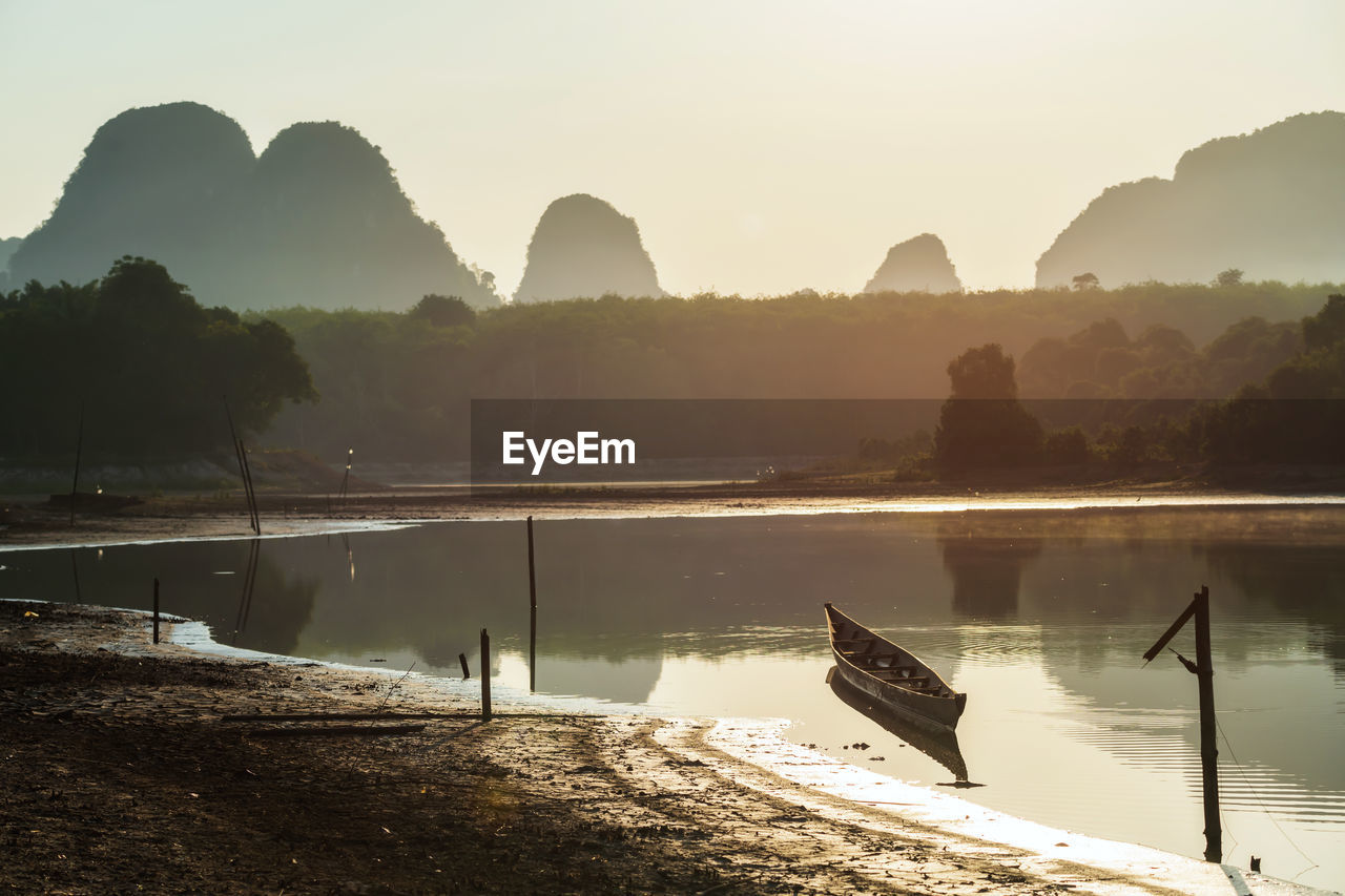 Scenic view of boat on lake against sky during sunrise