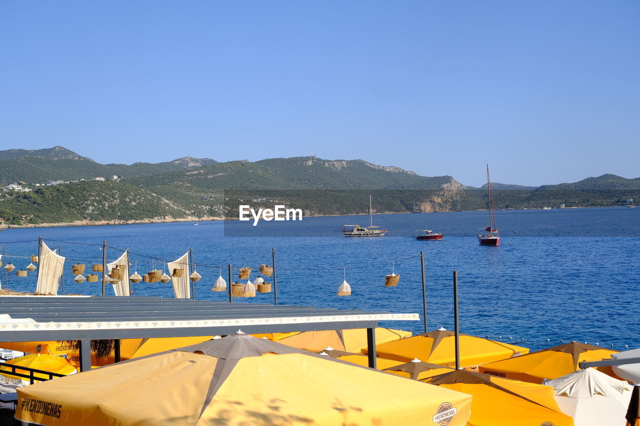 water, mountain, sky, sea, transportation, nautical vessel, nature, clear sky, blue, vehicle, travel destinations, land, mode of transportation, no people, sunny, travel, day, scenics - nature, mountain range, architecture, vacation, beach, boat, sunlight, beauty in nature, outdoors, harbor, moored, holiday, ship, tourism, tranquility, summer, trip, bay, pier, tranquil scene, coast, copy space, built structure