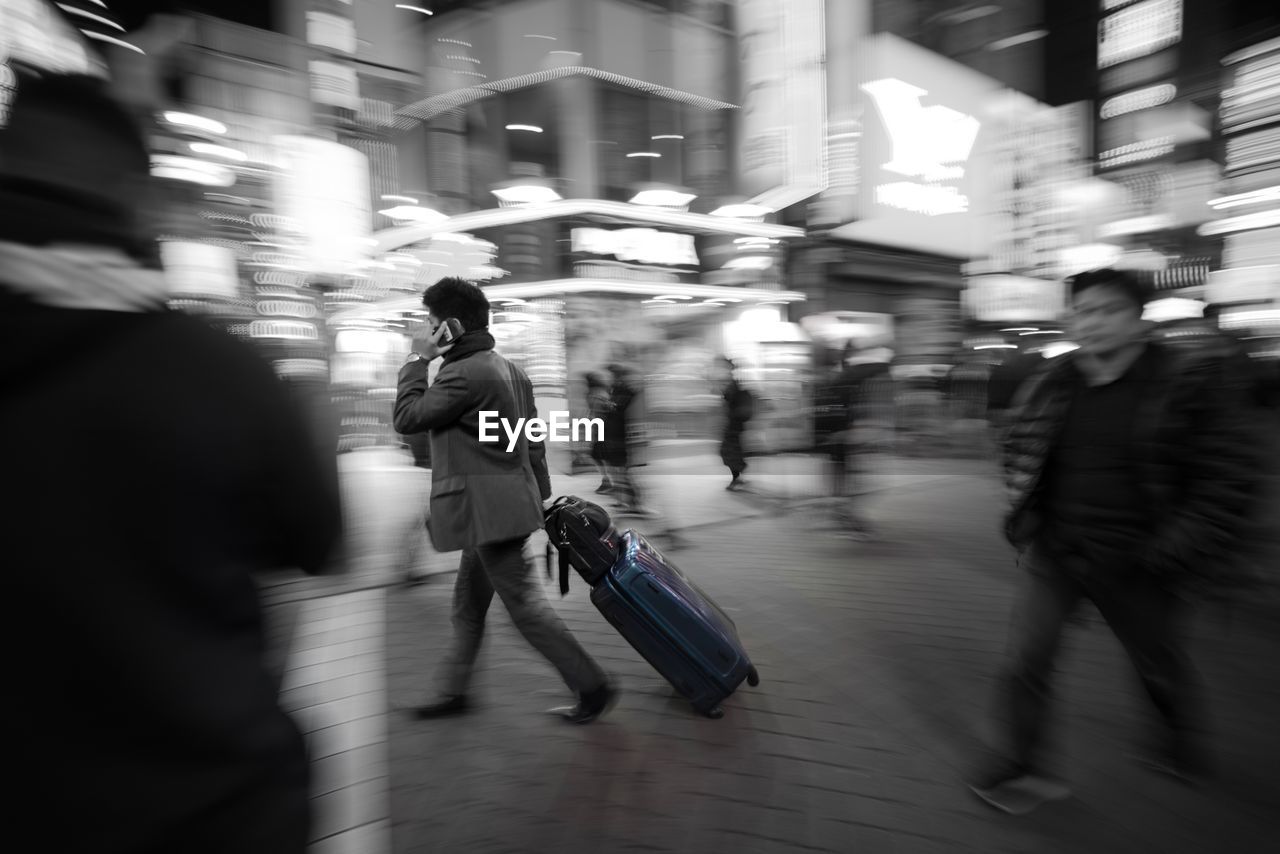 BLURRED MOTION OF MAN WALKING ON ILLUMINATED UNDERGROUND WALKWAY