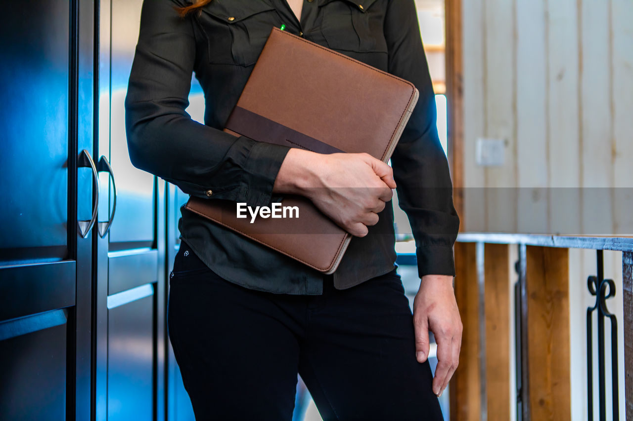 Midsection of woman holding file