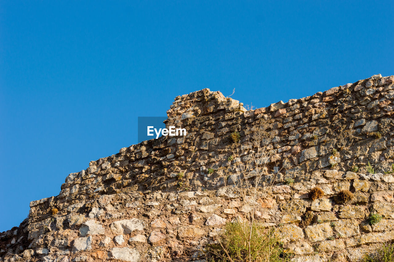 LOW ANGLE VIEW OF ROCKS AGAINST BLUE SKY