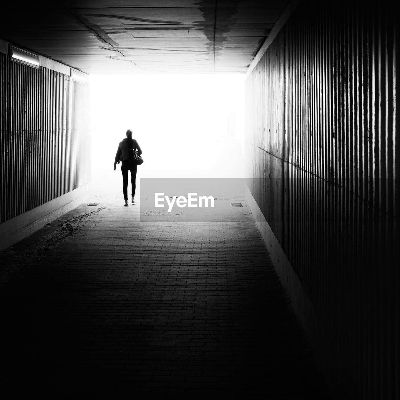 Rear view of silhouette woman walking in tunnel
