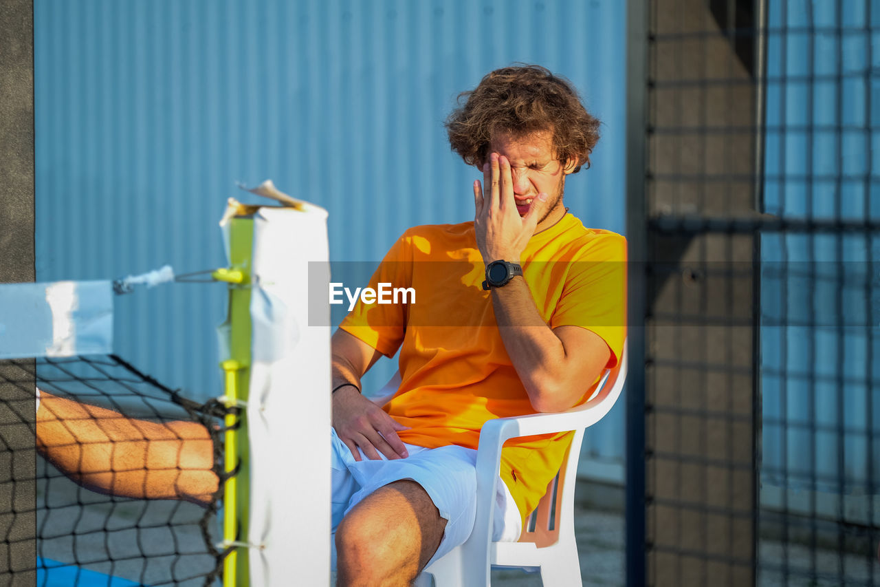 Tennis player sitting on chair at court