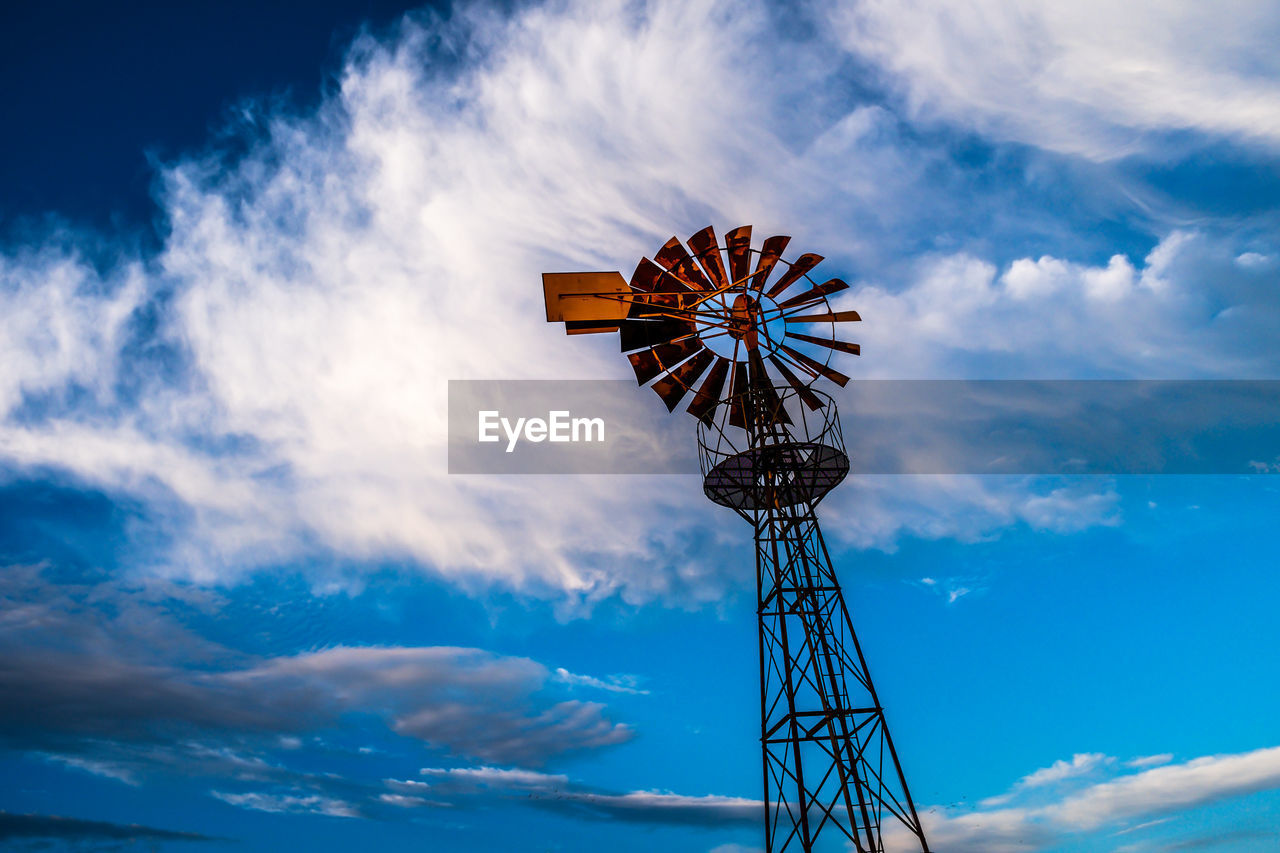 Low angle view of water pump windmill against clouds and sky