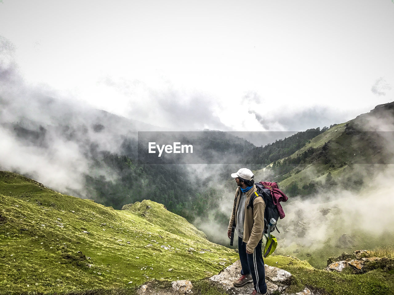 Hiker standing on mountain during foggy weather