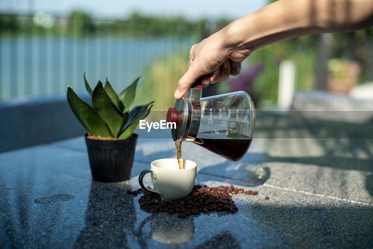 CLOSE-UP OF HAND HOLDING DRINK WITH GLASS