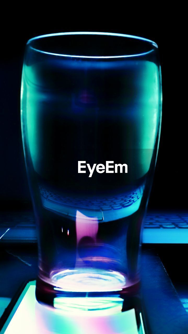 Close-up of drinking glass on illuminated light against black background