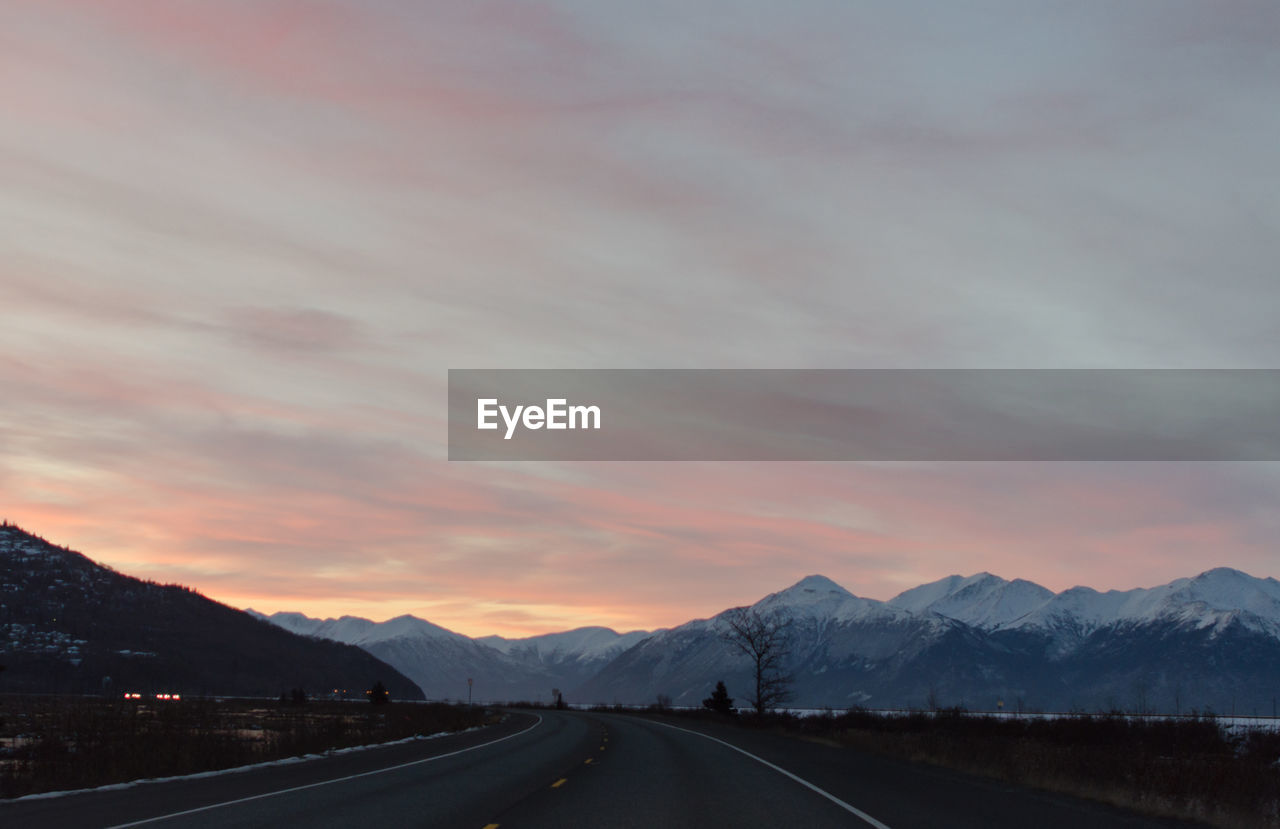 Road by mountains against sky