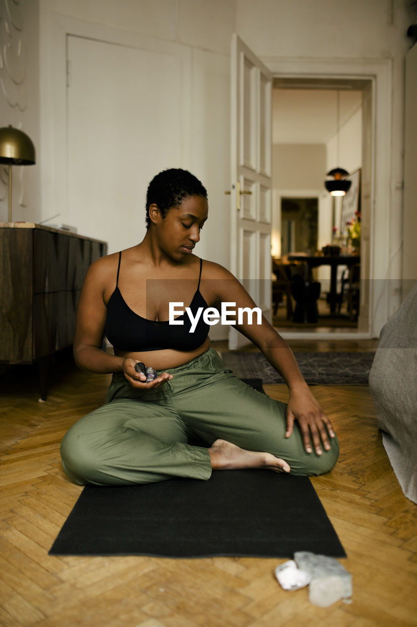 Young woman holding stones while practicing relaxation exercise at home