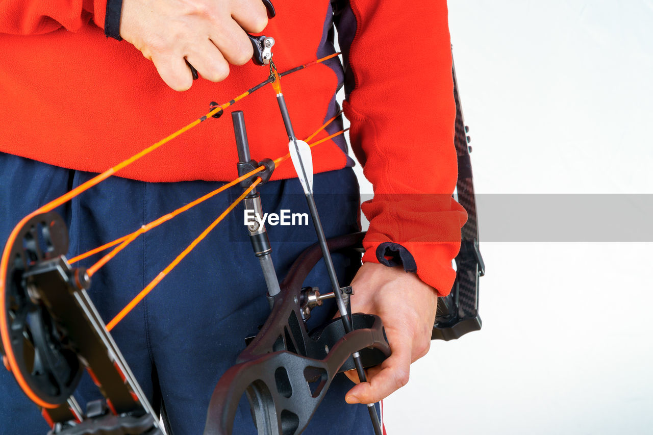 Midsection of archer holding cross bow against white background