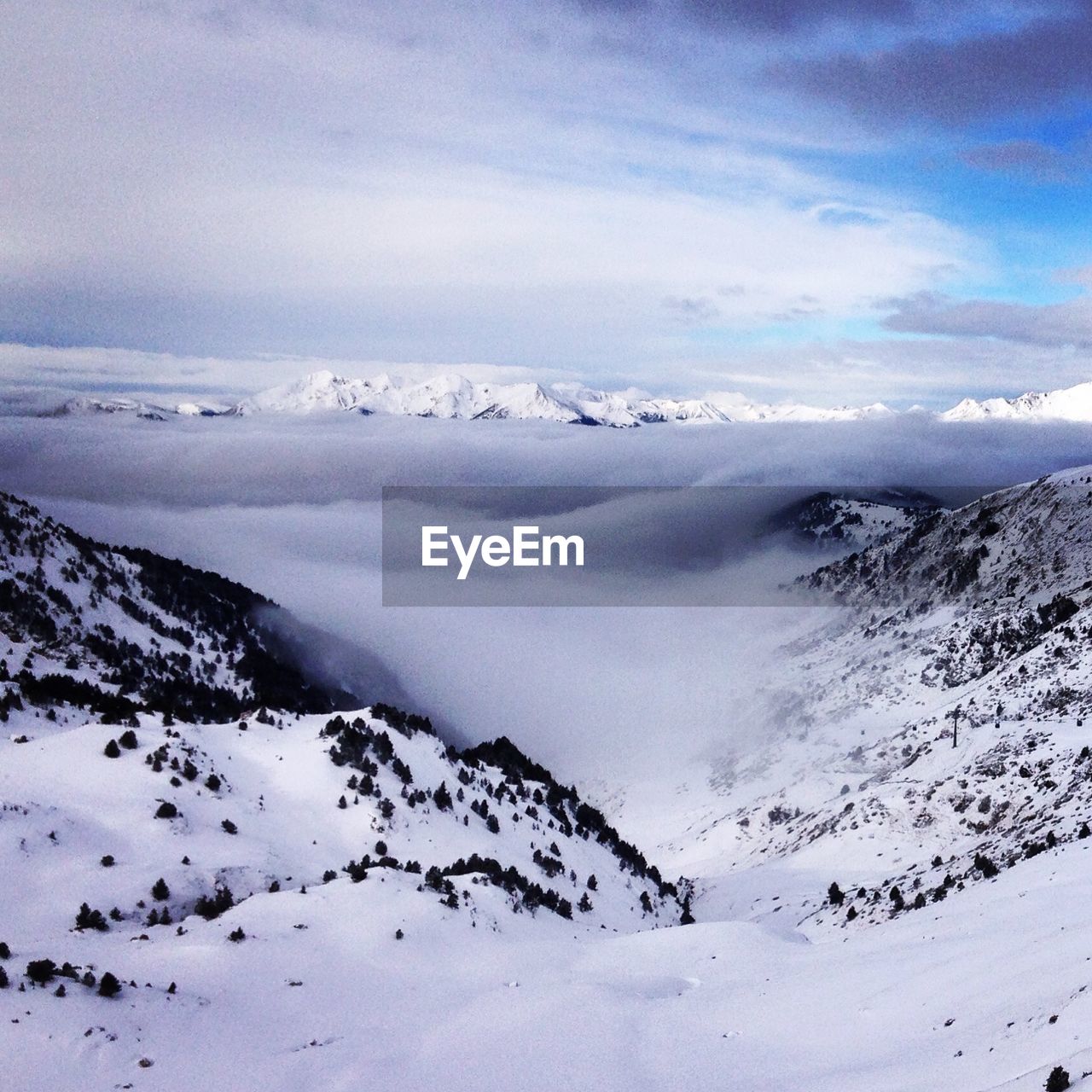 Scenic view of snow covered mountains against cloudy sky