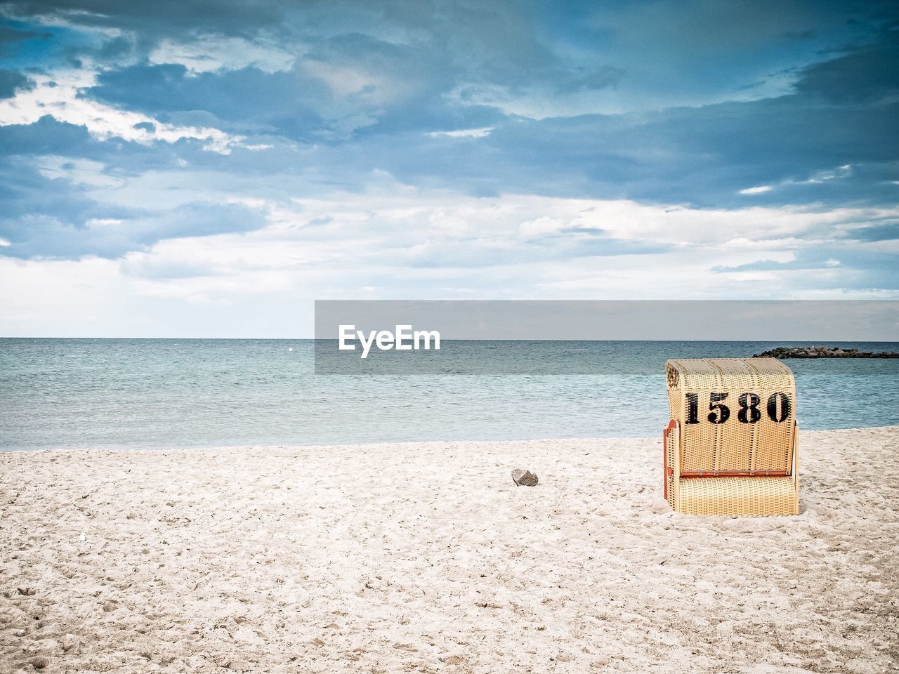 Hooded chair at beach against sky