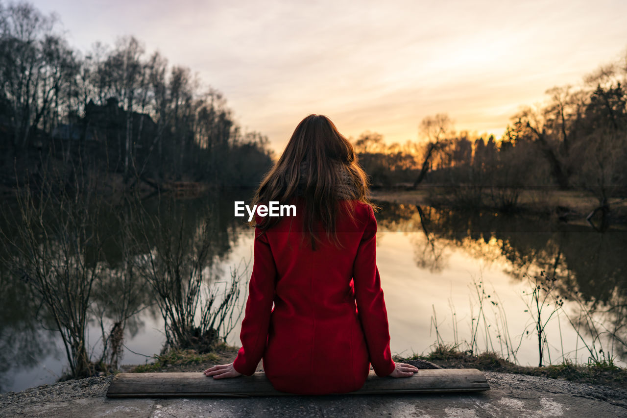 REAR VIEW OF WOMAN BY LAKE AGAINST SKY