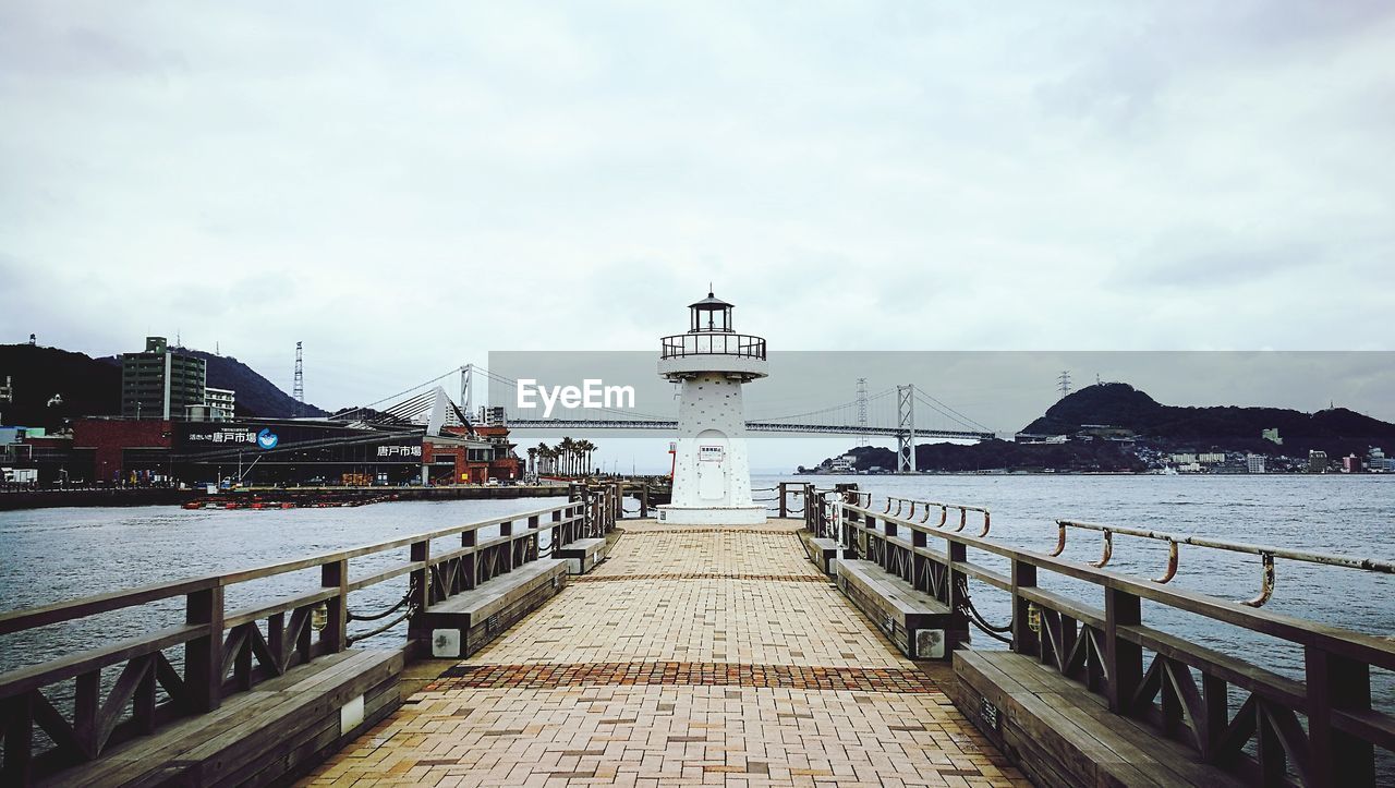 View of pier at harbor against cloudy sky