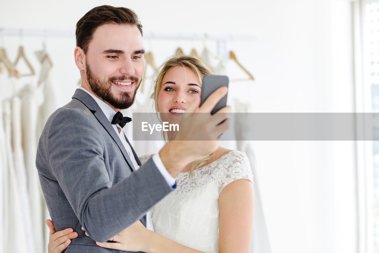 Smiling young couple taking selfie while using smart phone