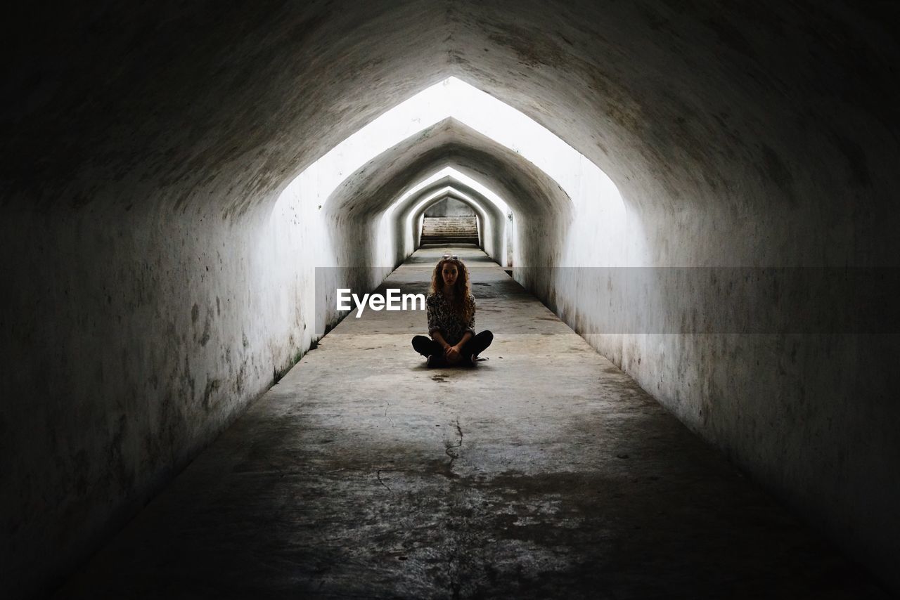 Portrait of young woman sitting in underground tunnel at taman sari