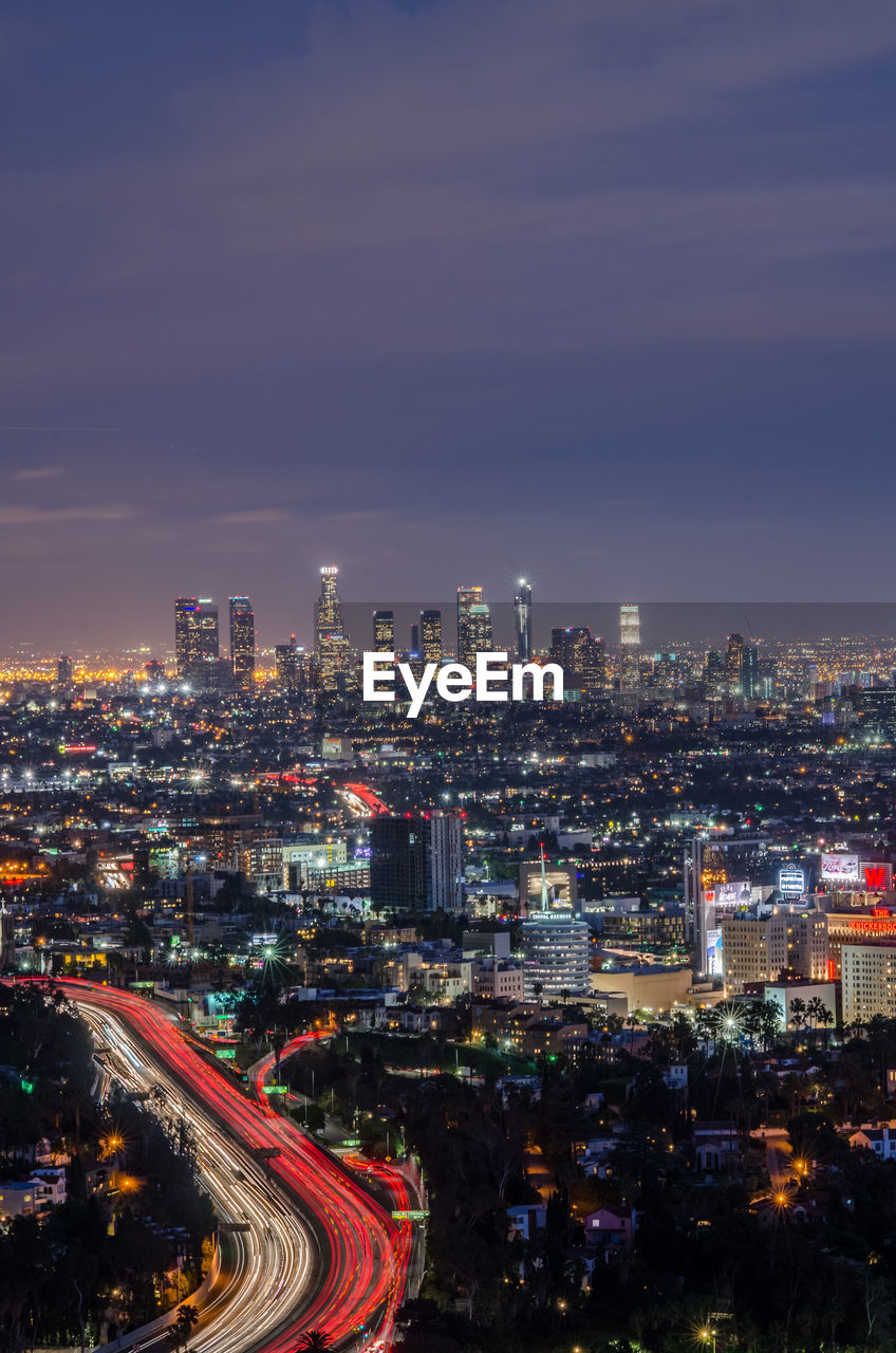 Illuminated cityscape against sky at dusk