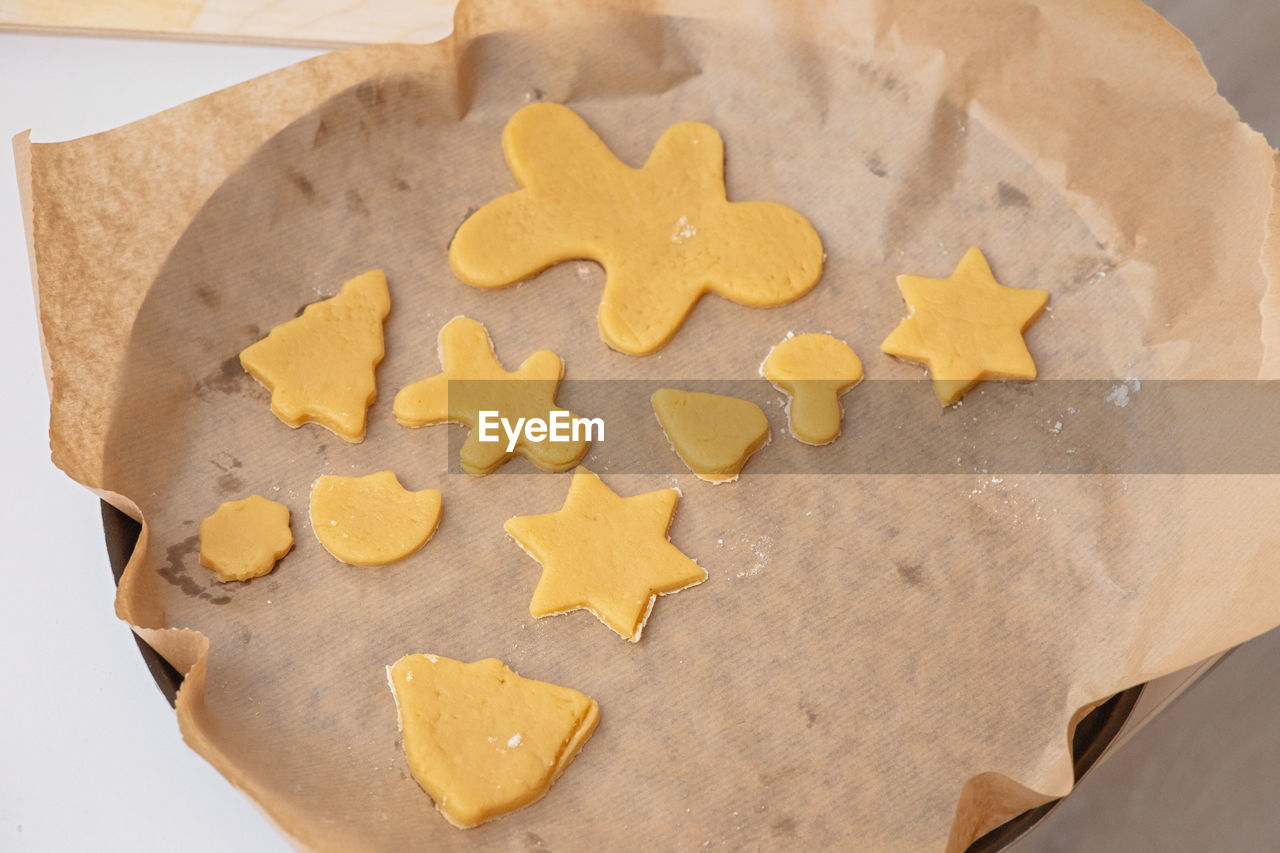 On the parchment are figurines made of raw dough in the form of christmas symbols