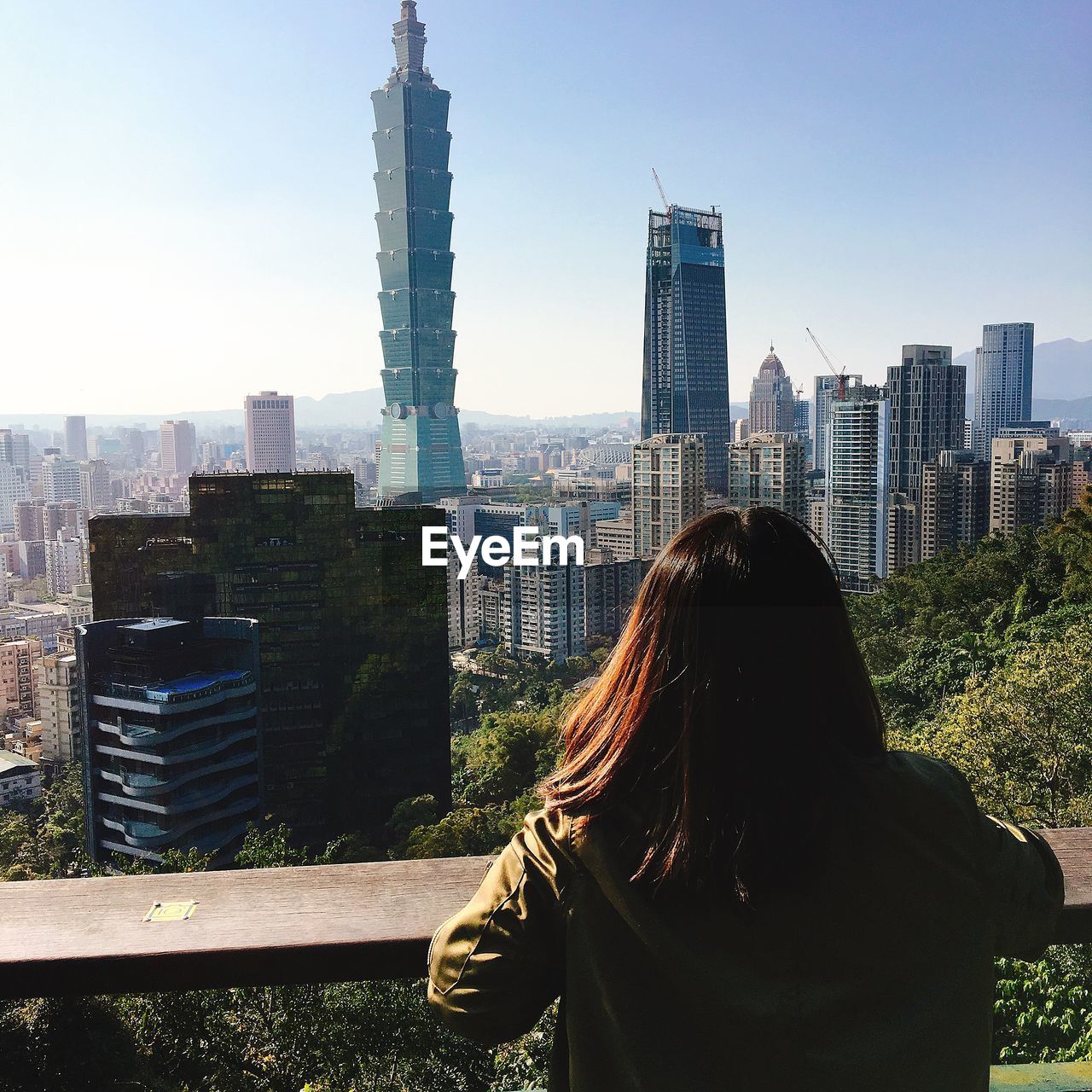 Rear view of woman standing against modern buildings in city