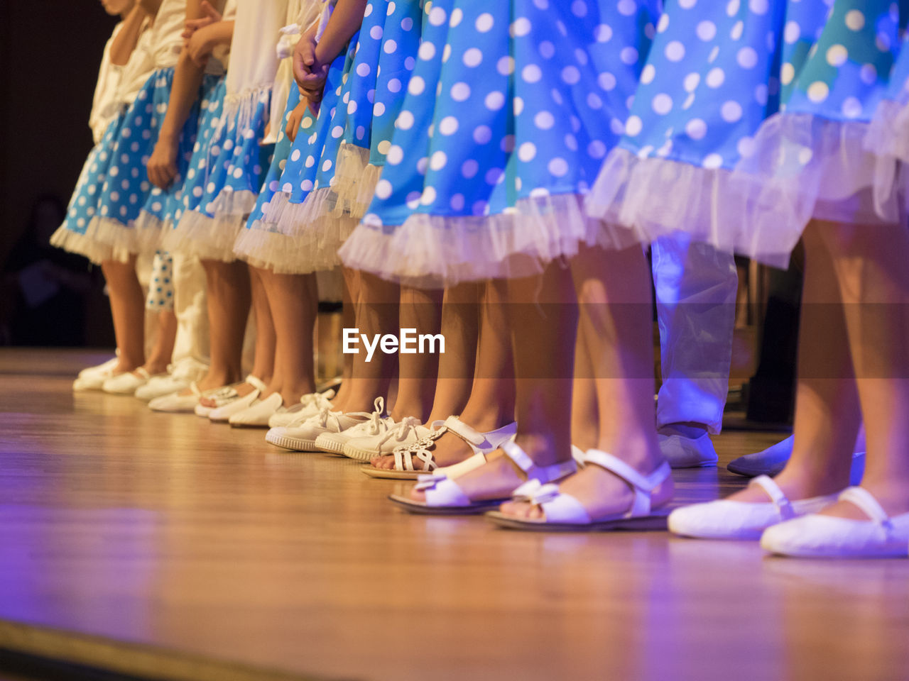 Low section of performers in blue skirt on stage