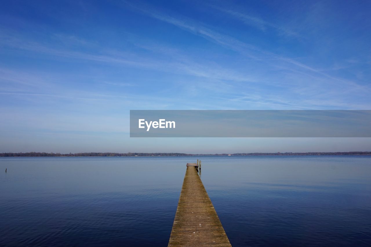 Pier over lake against blue sky