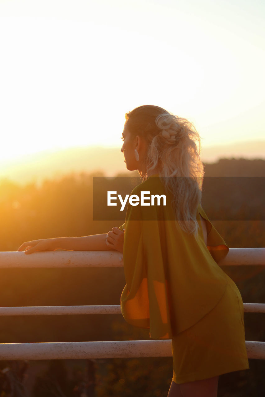 Backlighting portrait of beautiful woman in yellow dress at spring wedding with sunset light